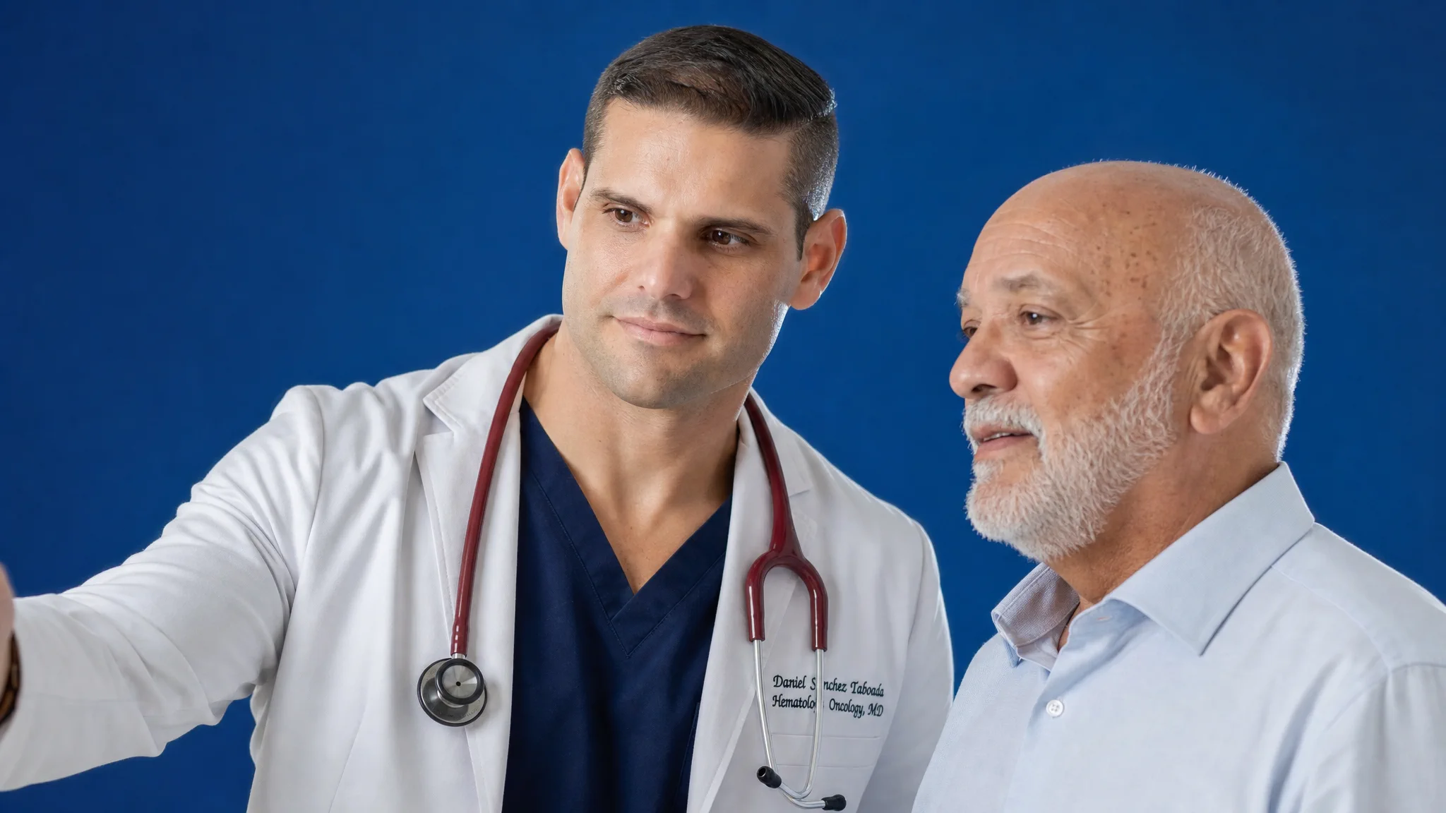 Dr. Daniel Sánchez Taboada conversa con un paciente sobre un fondo azul