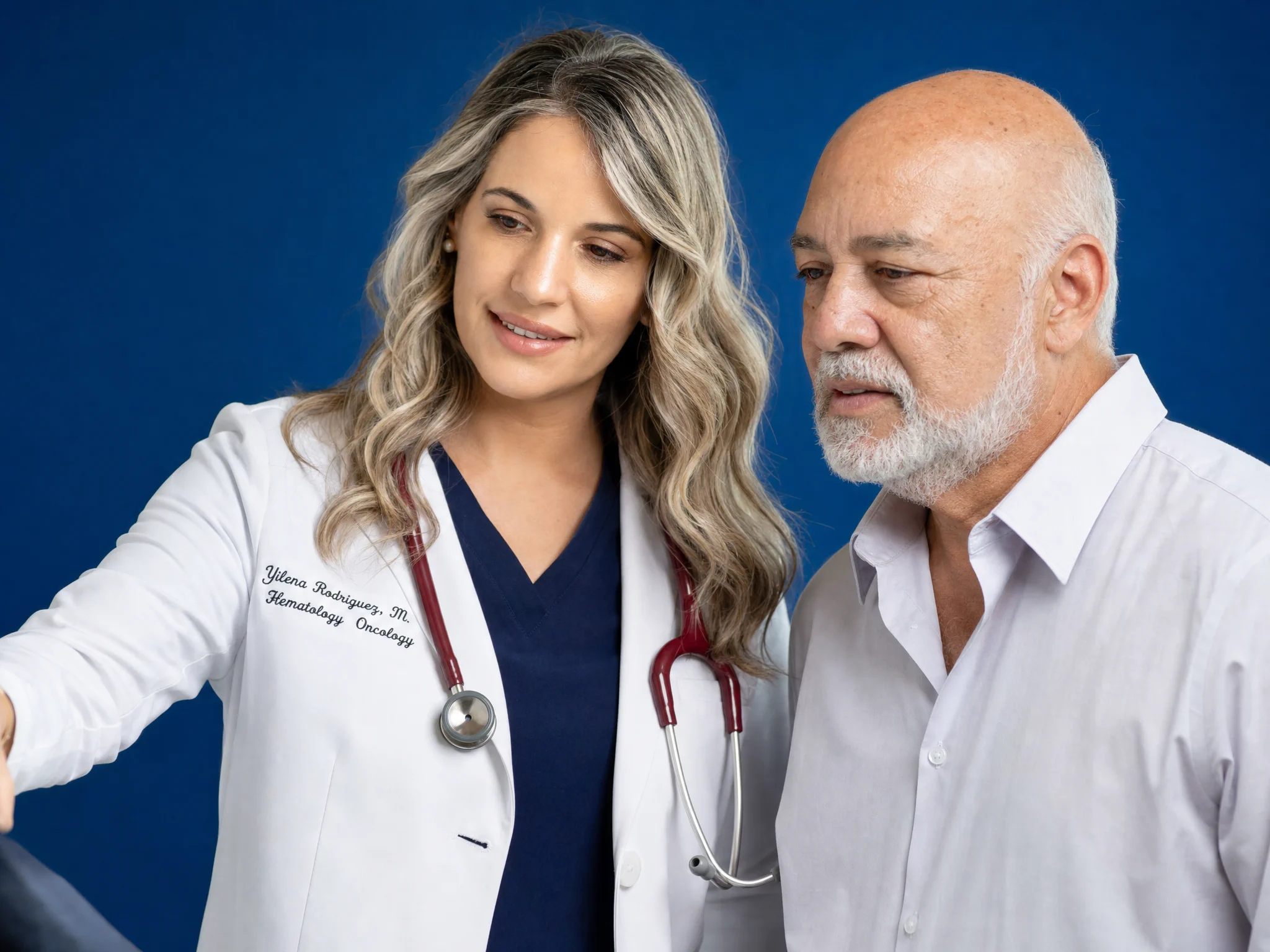 Tratamiento cerca de ti - infusión ambulatoria en Miami Dra. Yilena Rodríguez Marrero conversa con un paciente sobre un fondo azul